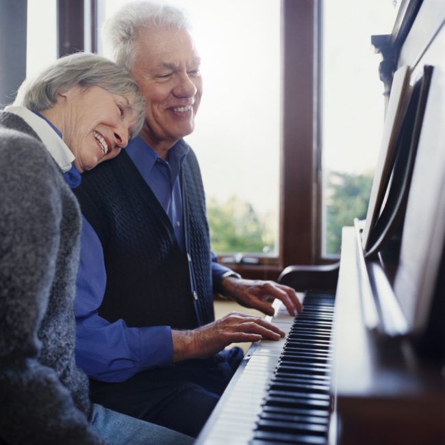 Older couple playing the piano in their home in Dallas, TX