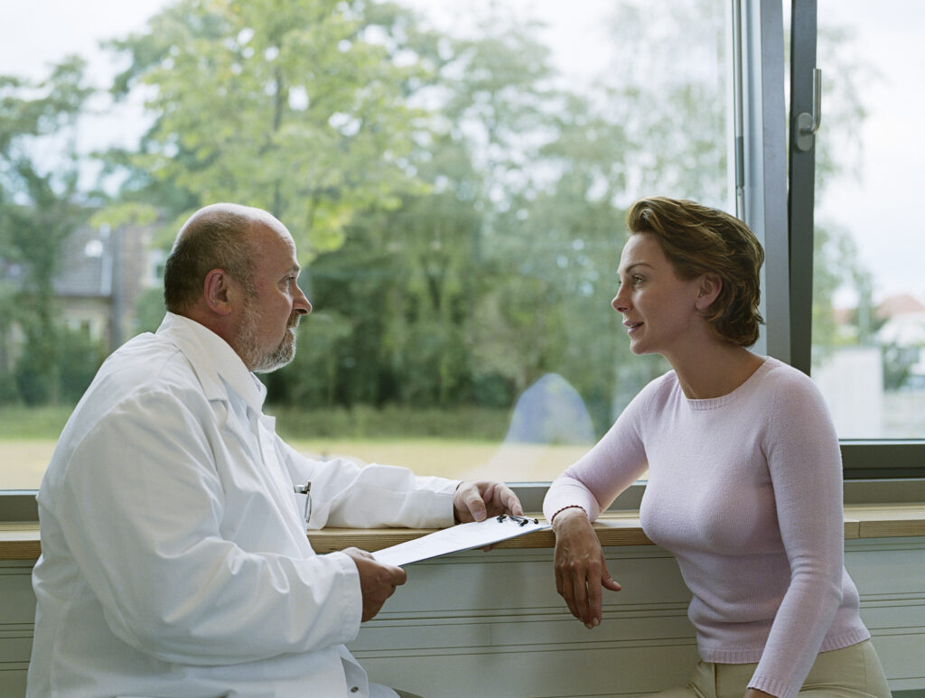 Male doctor having a conversation with patient by the window in Dallas, TX